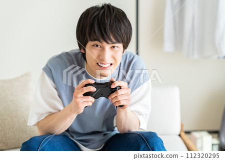 Young man playing video games in the living room 112320295