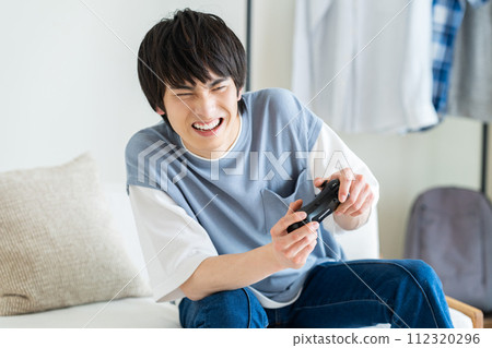 Young man playing video games in the living room 112320296