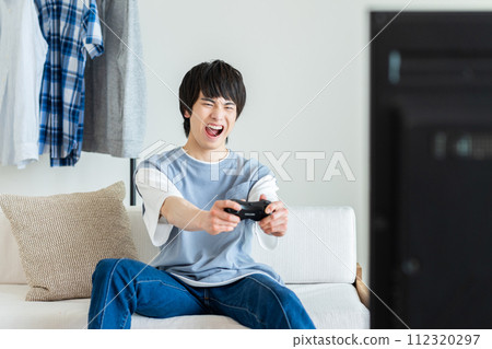 Young man playing video games in the living room 112320297