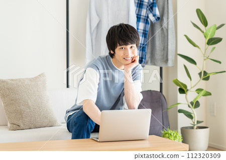 A young man looking at a personal computer in the living room 112320309