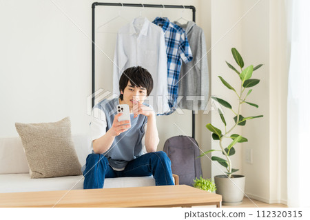 A young man looking at his smartphone in the living room A young man looking at his smartphone in the living room 112320315