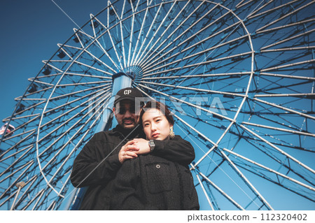 Men and women cuddling in front of the Ferris wheel Men and women cuddling in front of the Ferris wheel 112320402