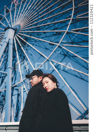 Men and women cuddling in front of the Ferris wheel 112320421