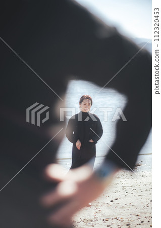 A woman standing behind a man on the beach 112320453