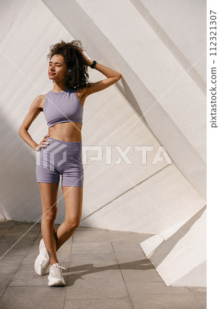 Young female athlete in sportswear have a rest after morning jogging outside and looks away 112321307