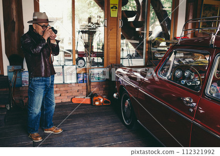 A picture of a senior man taking pictures of his favorite car as a hobby A picture of a senior man taking pictures of his favorite car as a hobby 112321992