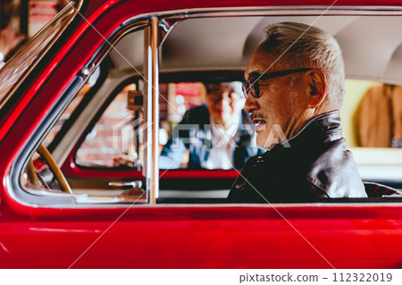 A picture of a senior couple having a conversation over their car 112322019