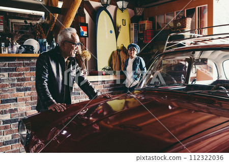 A picture of a senior couple having a conversation while looking at their car 112322036