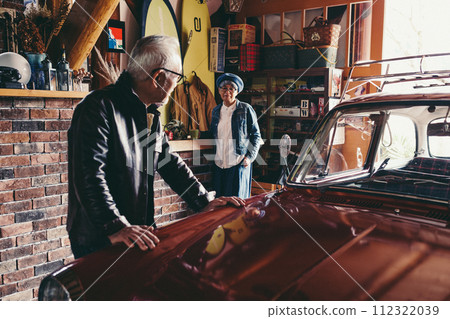 A picture of a senior couple having a conversation while looking at their car A picture of a senior couple having a conversation while looking at their car 112322039
