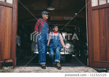 一對年長夫婦的時尚照片，他們的車停在車庫前 112322120