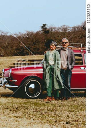 一對時髦的老年夫婦站在他們最喜歡的車旁的照片 112322580