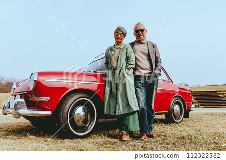 一對時髦的老年夫婦站在他們最喜歡的車旁的照片 112322582