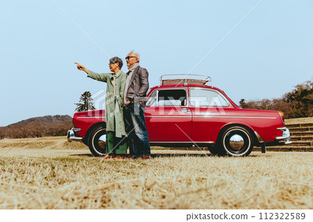 一對時髦的老年夫婦站在他們最喜歡的車旁的照片 一對時髦的老年夫婦站在他們最喜歡的車旁的照片 112322589