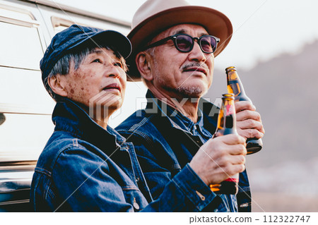 A picture of a senior couple standing while watching the sunset 112322747