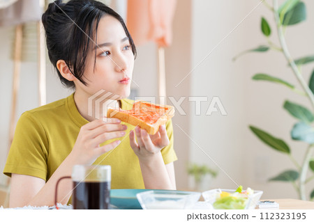 在客廳吃早餐的年輕女人 112323195