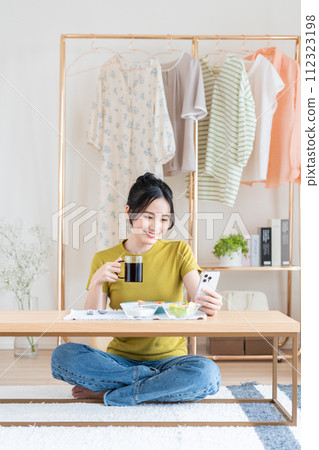 Young woman eating breakfast in the living room Young woman eating breakfast in the living room 112323198
