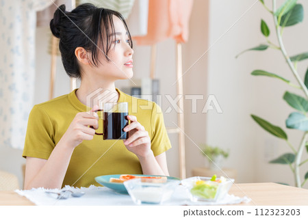 在客廳吃早餐的年輕女人 在客廳吃早餐的年輕女人 112323203