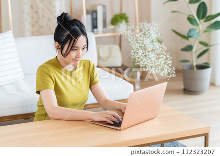 使用一台電腦在客廳裡的年輕女子 112323207