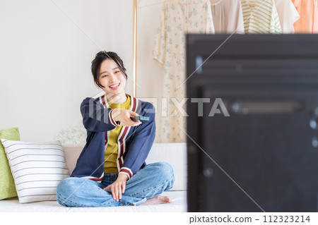 一位年輕的女士在客廳裡看電視 112323214