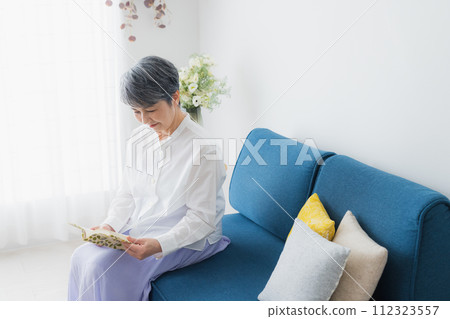 Senior woman reading in the living room 112323557