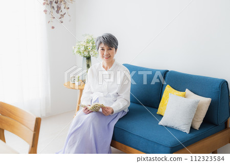 Senior woman reading in the living room 112323584