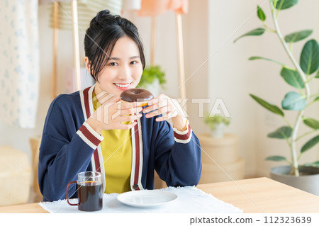 在客廳吃甜甜圈的年輕女人 112323639