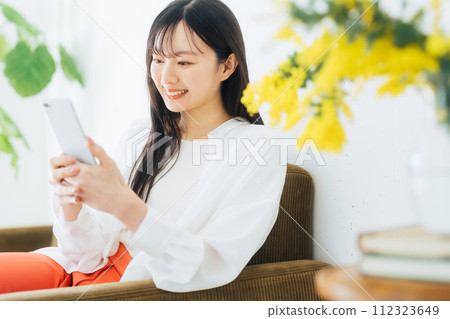 A young woman operating a smartphone A young woman operating a smartphone 112323649