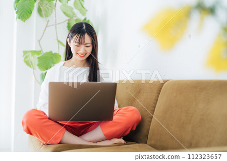 Woman using a computer on the sofa 112323657