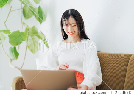 Woman using a computer on the sofa 112323658