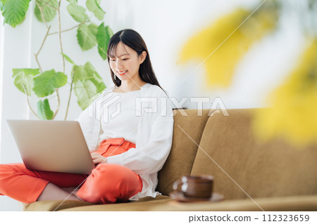 Woman using a computer on the sofa 112323659