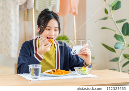 Young woman eating pasta in the living room Young woman eating pasta in the living room 112323663