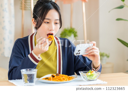Young woman eating pasta in the living room 112323665