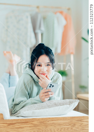 Young woman looking at her smartphone in the living room Young woman looking at her smartphone in the living room 112323779