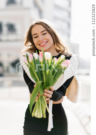 Happy young woman with tulip flowers outdoors 112323829