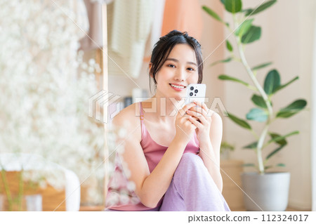 年輕女子在客廳看智慧型手機 112324017