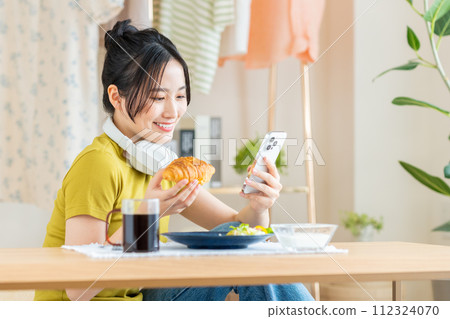 Young woman eating breakfast in the living room 112324070