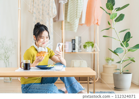 在客廳吃早餐的年輕女人 在客廳吃早餐的年輕女人 112324071