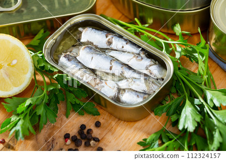 Open can of sardines on table 112324157