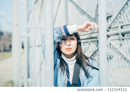 A woman leaning into a fence A woman leaning into a fence 112324312