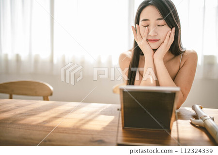 A woman taking care of her skin while basking in the morning sun A woman taking care of her skin while basking in the morning sun 112324339