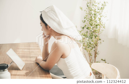 Young woman doing skin care by the window in the morning 112324412