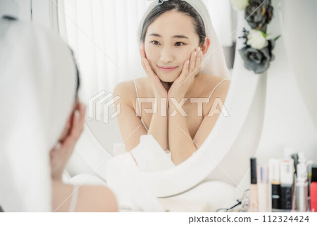 Young woman doing skin care while looking in the mirror 112324424