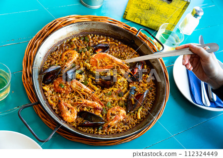 Cook serving seafood paella 112324449