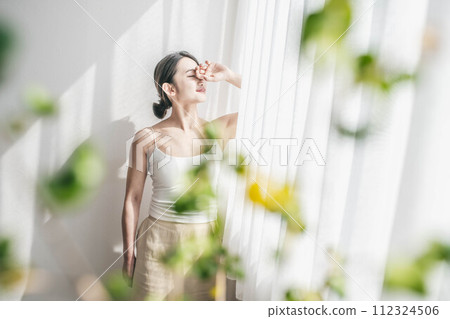晨光中沐浴在充滿自然的窗邊的女人 晨光中沐浴在充滿自然的窗邊的女人 112324506