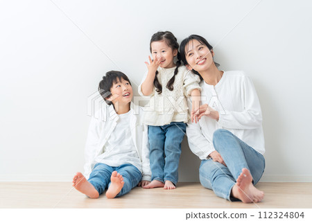 Parent and child relaxing against a white wall 112324804