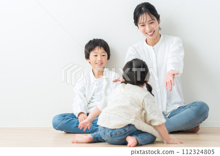 Parent and child relaxing against a white wall 112324805