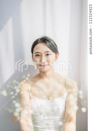A woman standing by the window with a hazy grass 112324923