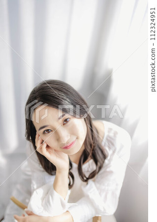 一個女人坐在靠窗的椅子上，手托著臉頰 112324951