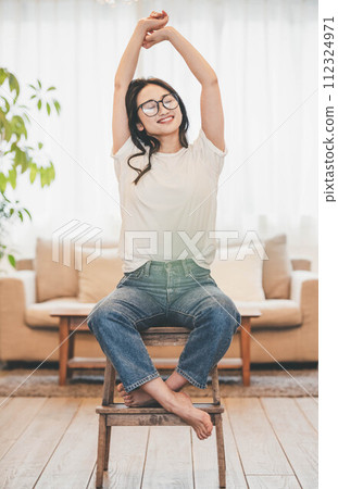 Long-haired glasses woman sitting on a chair in casual clothes 112324971