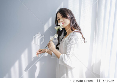 Woman with flowers standing by the window 112324986